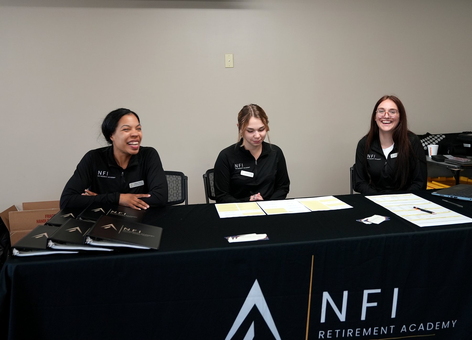 NFI Retirement Academy team members laughing together at a seminar registration desk