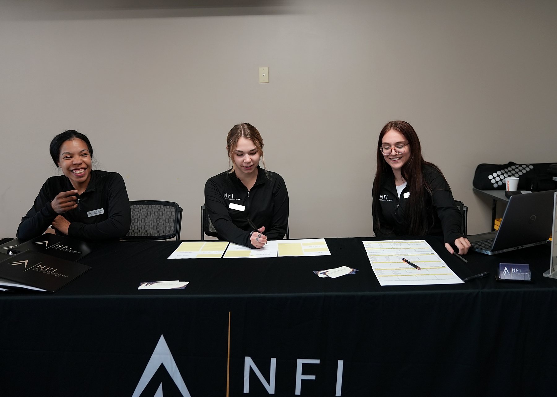 Academy team members working together at a branded seminar registration table